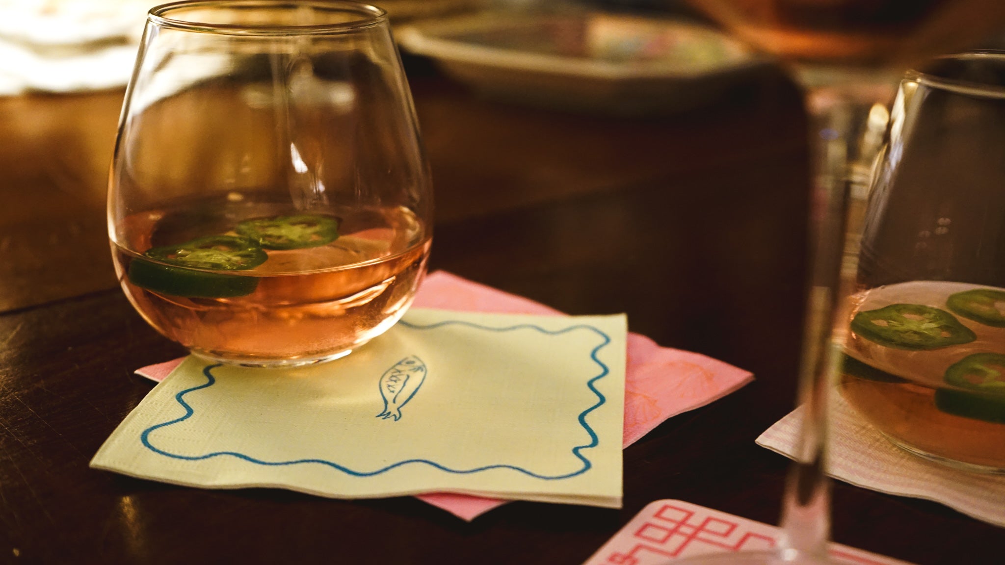 Glass of amber liquid with a fish print on a napkin, blurred background