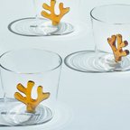 Clear glass tumblers with orange coral-like decorations on a light gray background